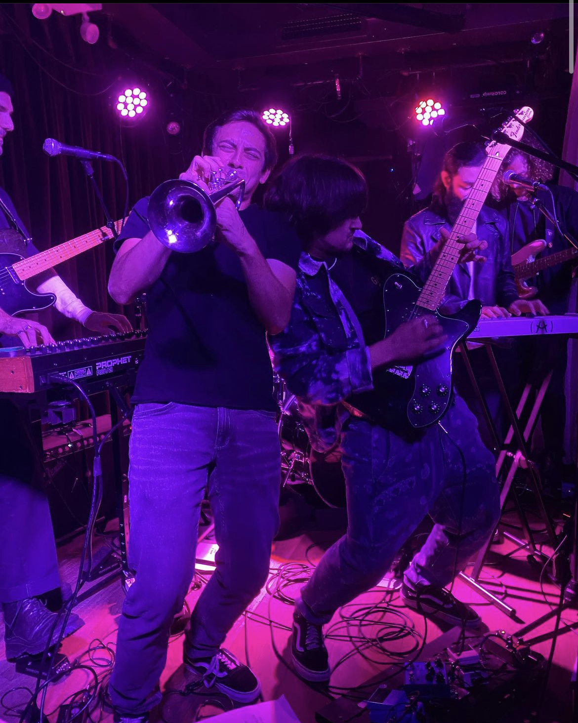 Dylan Satow playing trumpet on stage with purple lighting